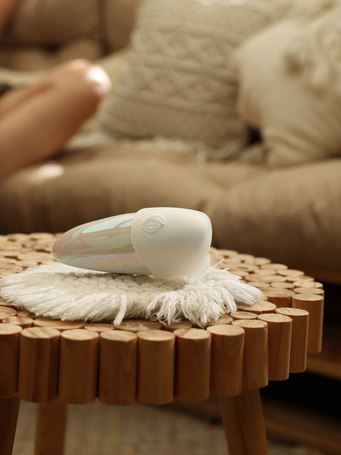 White handheld cleaning device on a wooden stool with a blurred sofa in the background