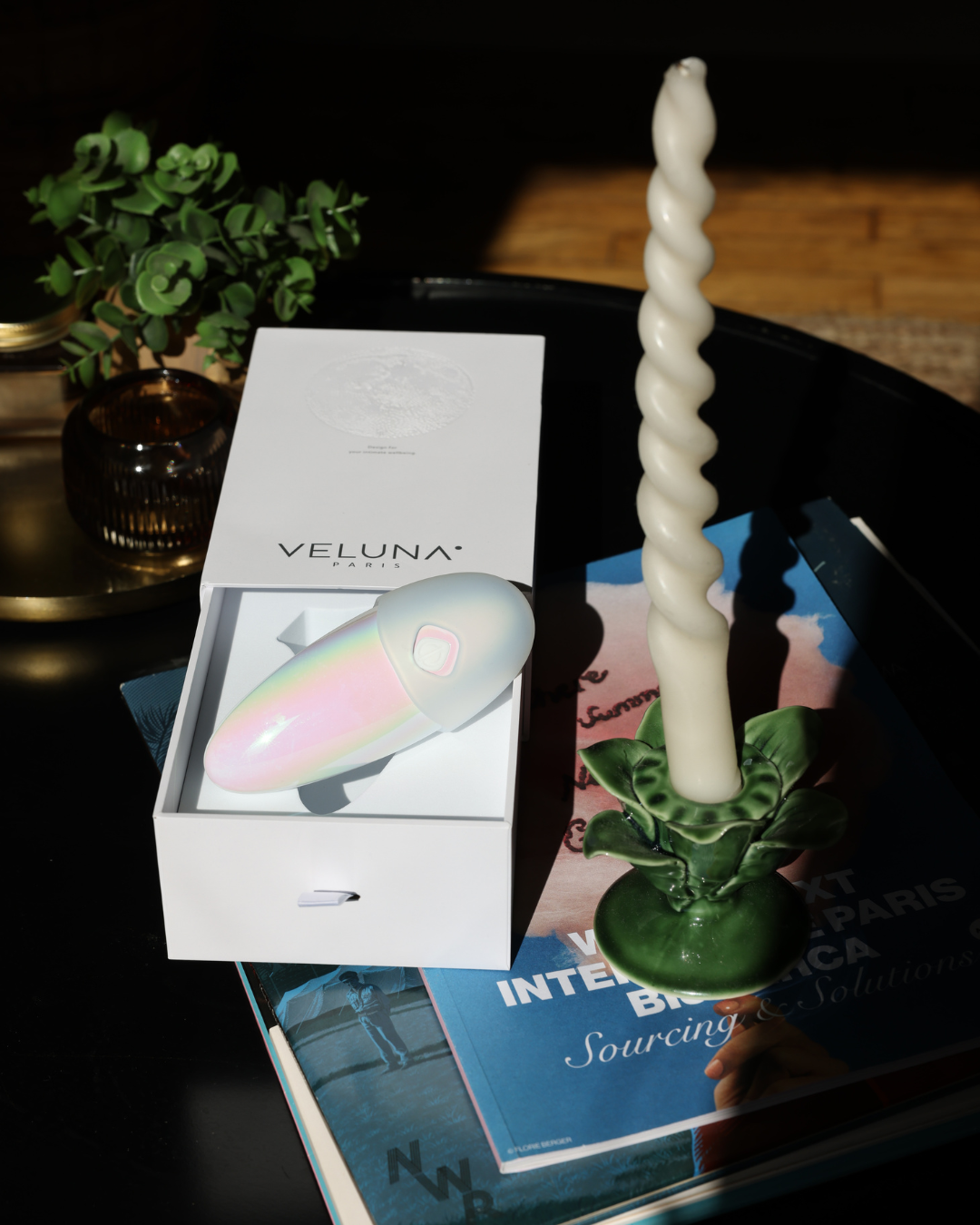 Twisted candle on a stand with Veluna product packaging in the background