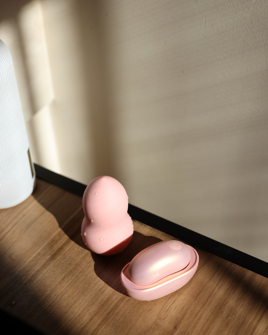 Pink egg-shaped container on a wooden surface with a neutral wall background